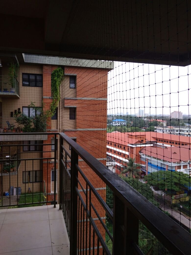 Black anti pigeon net installed on brick building façade matching the building aesthetics